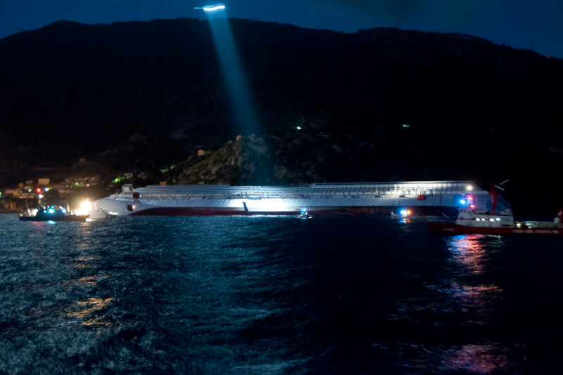 Lo scafo della Costa Concordia inclinato davanti all'Isola del Giglio con i primi soccorsi