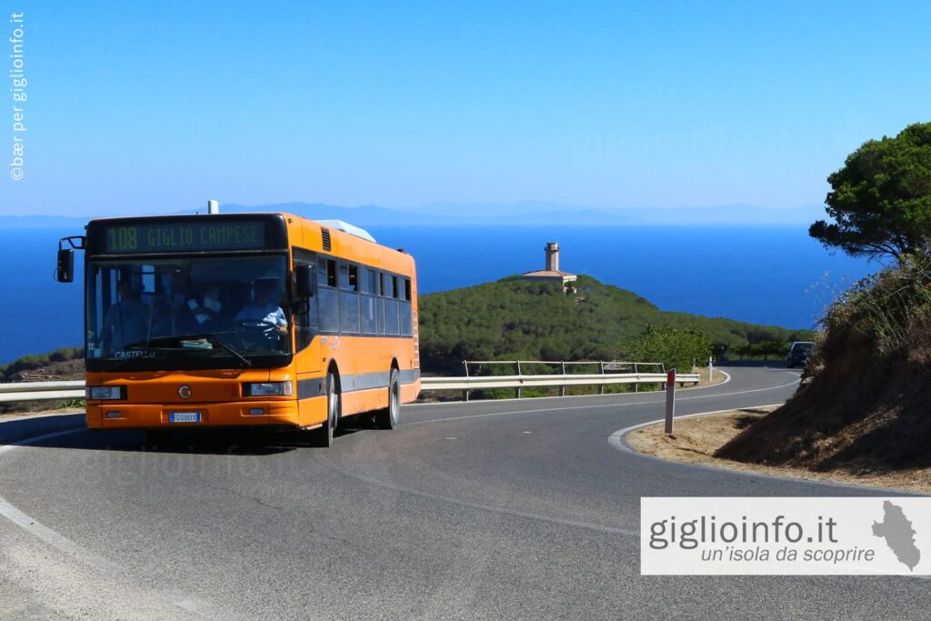 Autobus sulla strada dell'Isola del Giglio con vista antico faro e mare