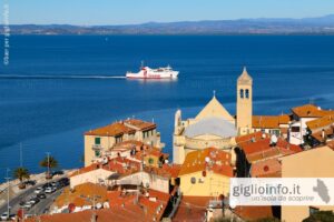 Traghetto Toremar in arrivo a Porto Santo Stefano con paese chiesa