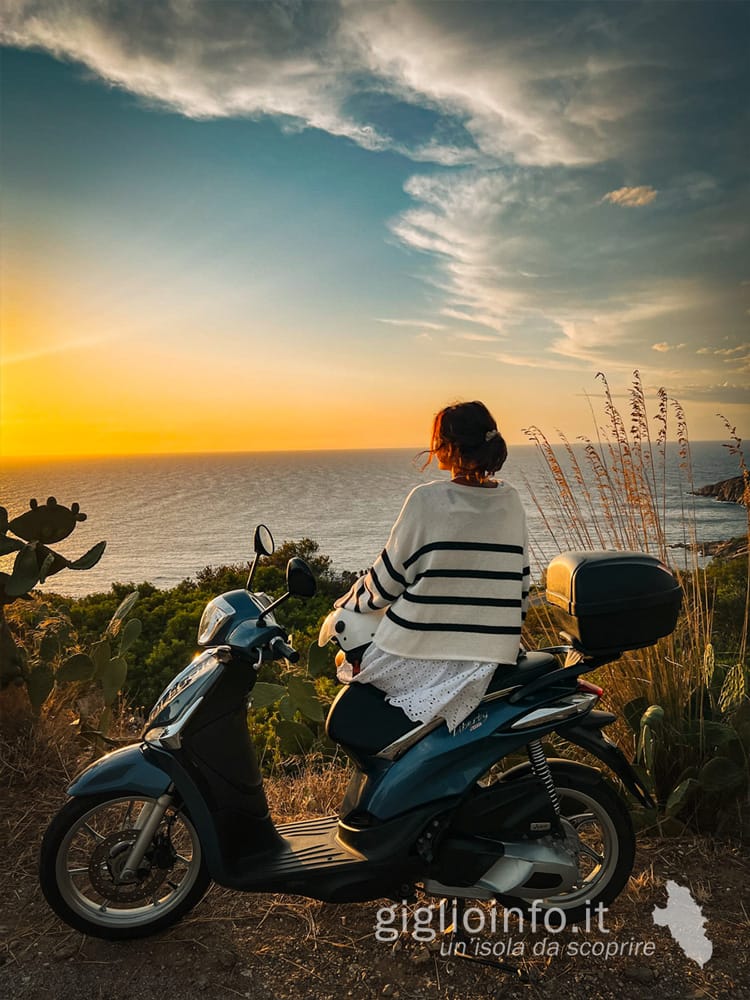 Ragazza sullo scooter che si gode il tramonto nella baia di Campese - Giglionoleggio Noleggio Scooter Isola del Giglio Porto