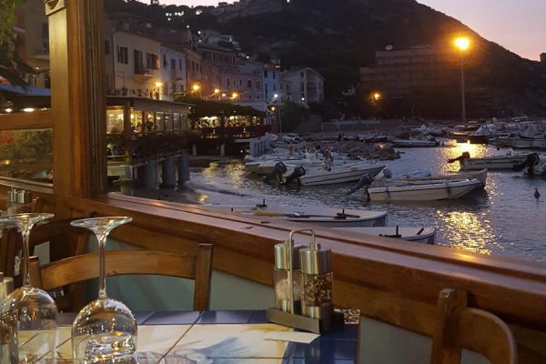 Sala con vista portoicciolo la sera Ristorante da Meino Isola del Giglio Porto